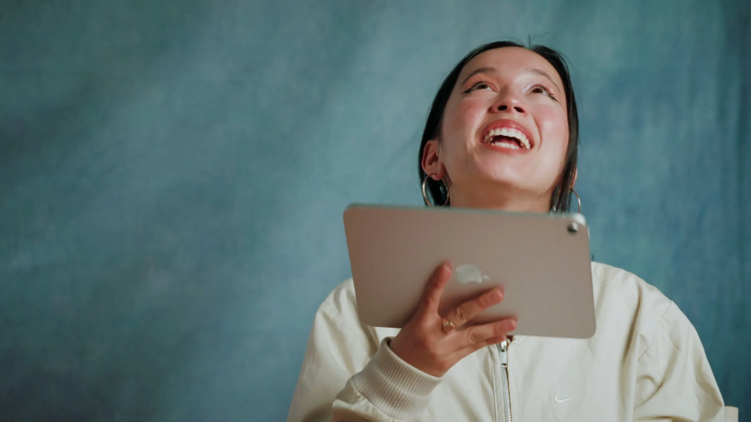 Filiz éclate de rire en écoutant un morceau, tablette à la main